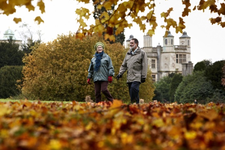 A couple walking across fallen orange leaves at an english heritage site