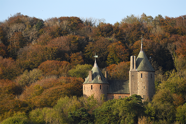 cadw castle turrets surrounded by orange leaved trees